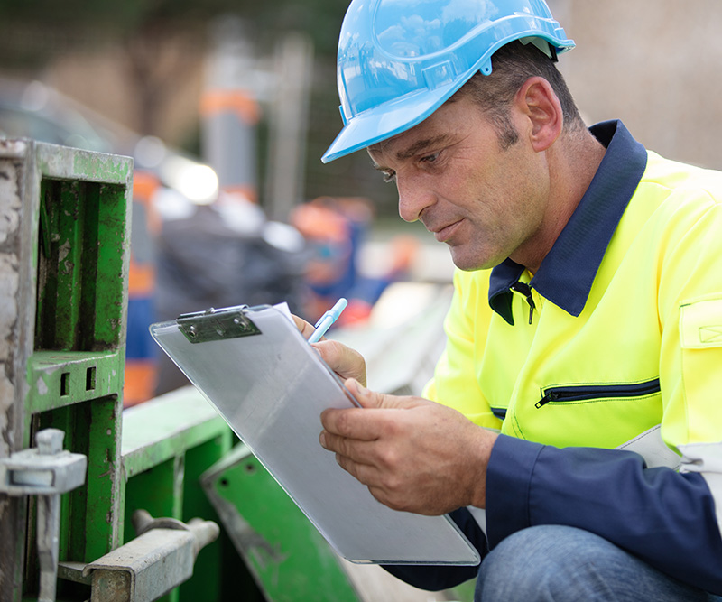 construction worker taking notes on clipboard at job site for safety routine inspections